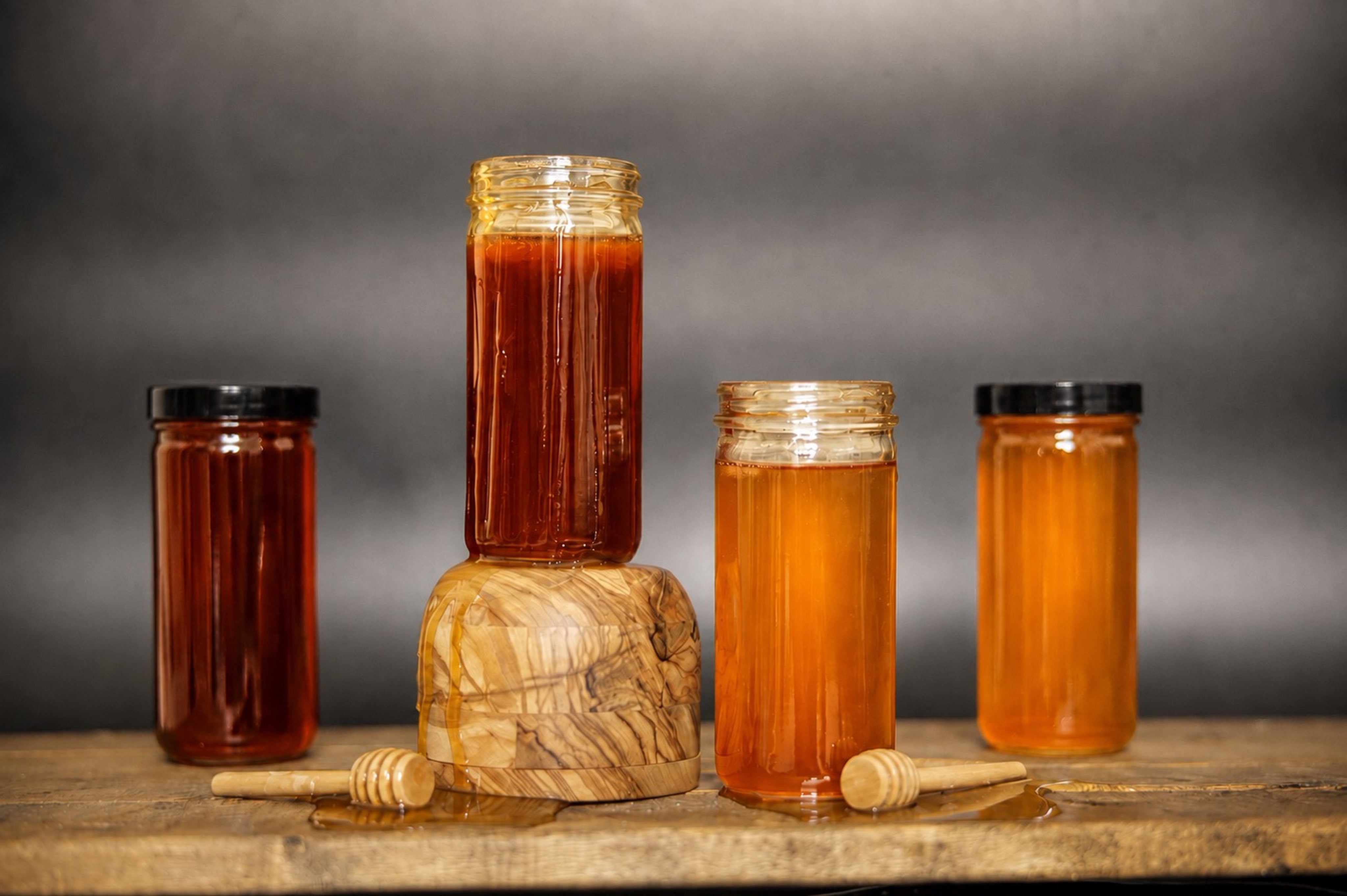 Four jars of honey in graduating ambers on wood