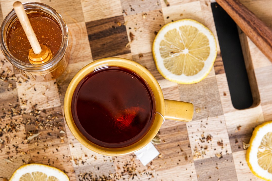 A mug of tea with honey and lemon on a cutting board